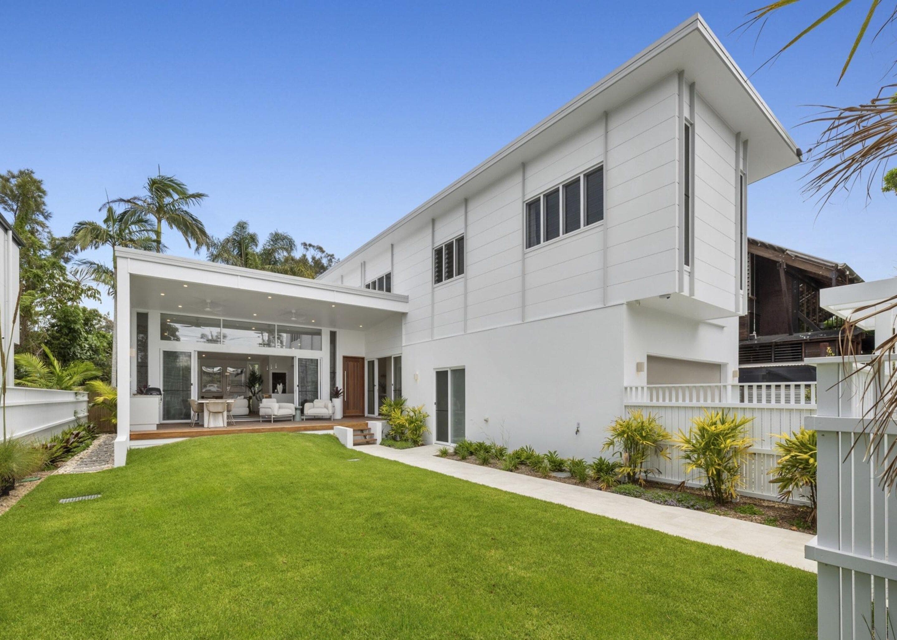 A modern two-story house with a covered patio and a well-maintained lawn.
