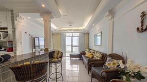 A spacious living area with a kitchen, a dining area, and a view of the ocean. - Apartamento na Praia Grande com Acesso a Praia (Praia Grande)