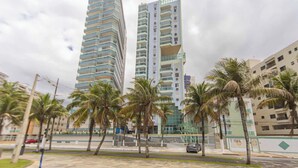 A modern high-rise building with a unique architectural design, featuring multiple balconies and a glass facade. - Apartamento na Praia Grande com Acesso a Praia (Praia Grande)