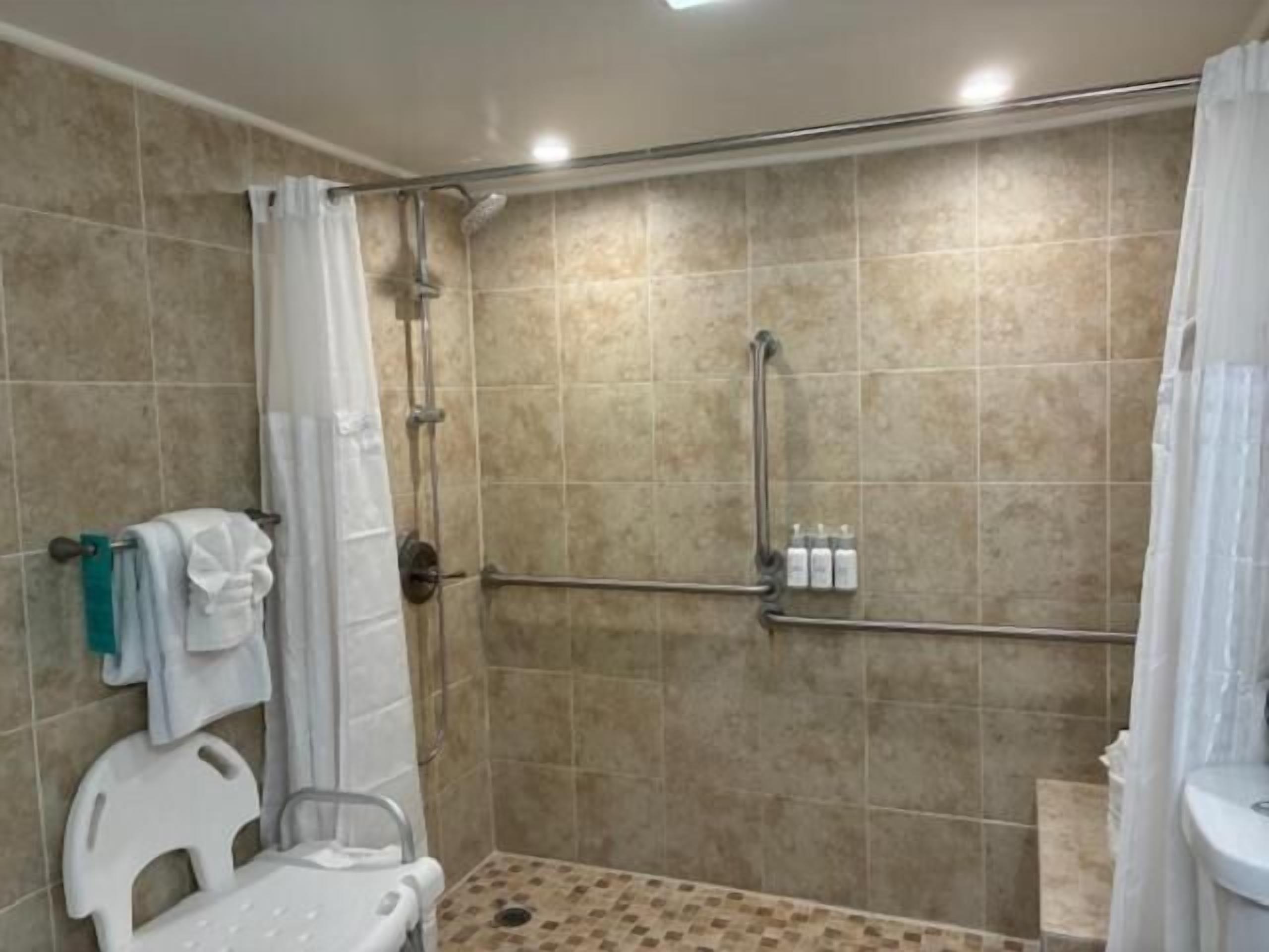 A shower area with a glass door, a white toilet, and a grab bar.