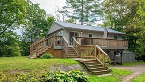 Une maison à deux étages avec une terrasse en bois et un escalier menant à l’étage supérieur.