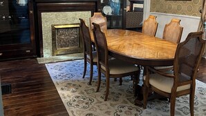 A dining room with a wooden table, six chairs, a chandelier, patterned wallpaper, and a fireplace. - Historic Kugler Cottage, built 1871, Charming 5-Bedroom Stay (Oil City)
