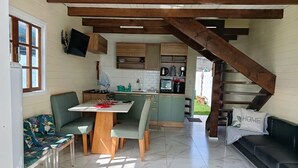 Una cuina compacta amb zona de menjador, una escala i zona d'estar amb sofà.
