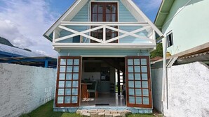 Una casa de dues plantes amb teulada a dos vessants, una cuina oberta i una porta d'entrada amb panells de vidre.