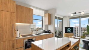Une cuisine moderne avec des meubles en bois, un four encastré, un évier et une grande fenêtre donnant sur la ville.