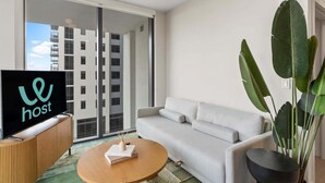 Un salon moderne avec un canapé, une table basse et un téléviseur posé sur une console en bois.