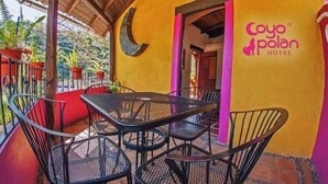 Un patio con mesa y sillas, una decoración con forma de luna creciente y un cartel del Hotel Cayo Polan.