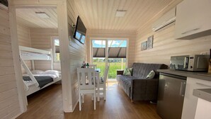 A cabin interior with a bunk bed, a sofa, a dining table, a microwave, and a dishwasher. - Comfortable Holiday Homes With air Conditioning (Darlowo)