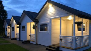 A row of white cabins with sloped roofs, each with a porch and steps leading to the entrance. - Comfortable Holiday Homes With air Conditioning (Darlowo)