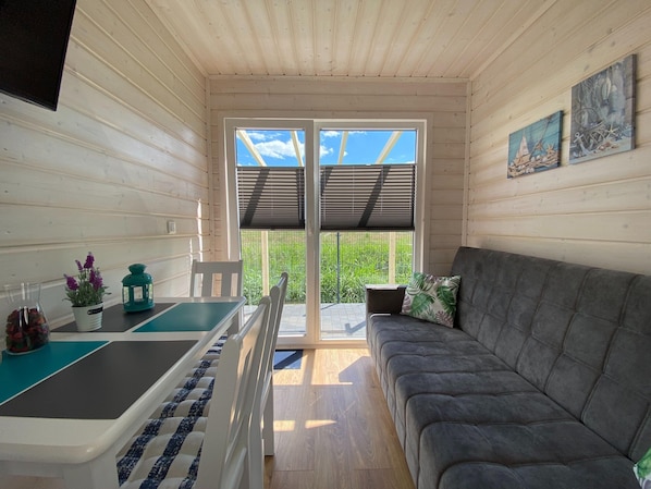En ombonad inredning med en soffa, ett litet bord och utsikt över grönskan utanför.