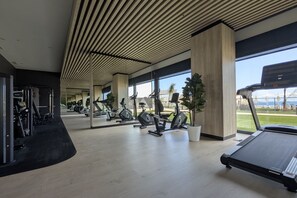 Ein modernes Fitnessstudio mit Trainingsgeräten, großen Fenstern und Blick ins Freie.