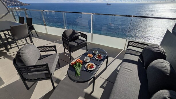 A balcony with a table set for breakfast, overlooking a coastal view. - SUNSET SAILORS sea & sky apartment (Benidorm)