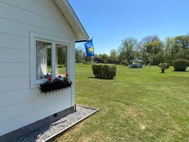 Una casa con ventana, una bandera y un césped bien cuidado.