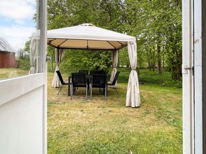 A covered outdoor seating area with a table and chairs, surrounded by trees. - 6 Person Holiday Home in Lottorp (Löttorp)