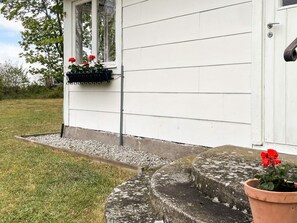 A white house with a window-mounted planter and a potted plant on the steps. - 6 Person Holiday Home in Lottorp (Löttorp)