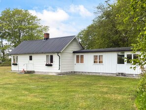 A two-story white house with a dark roof, a chimney, and a small porch with flower boxes. - 6 Person Holiday Home in Lottorp (Löttorp)