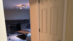 A room with a fireplace, a bed, and a door. - Private Luxury 2 Bedroom Suite (Framingham)