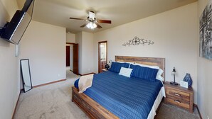 Un dormitorio con una cama grande, cabecera de madera, ventilador de techo, mesita de noche, lámpara y espejo.