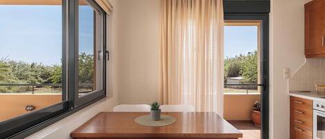 Un comedor con mesa y sillas, vistas al exterior y una cocina con armarios y estufa.