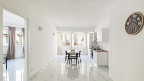 A modern interior with a dining area, kitchen, and a hallway leading to an open space with a view. - Posta Suites - 1br/4p - a Ventimiglia (Ventimiglia)