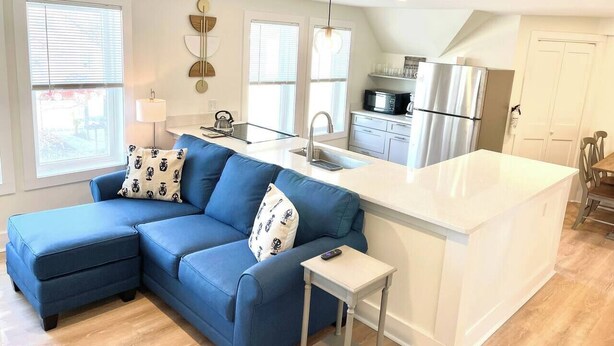 Eine moderne Küche mit einem blauen Ecksofa, einer weißen Kücheninsel und einem Edelstahl-Kühlschrank.