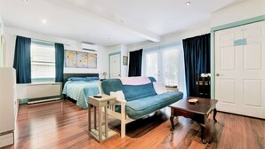 A room with a bed, a sofa, a small table, and a wardrobe. There is a window with curtains and a map on the wall. - Radiant Studio in the Heart of Bar Harbor (Bar Harbor)
