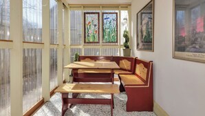 A room with a wooden table and benches, large windows with frosted glass, and a framed picture on the wall. - Radiant Studio in the Heart of Bar Harbor (Bar Harbor)