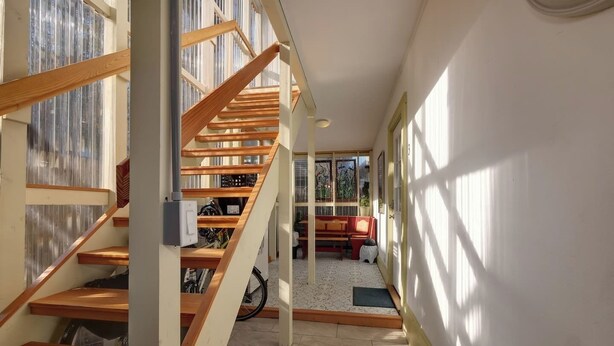 A staircase with wooden steps leading to a lower level, a red sofa, and a bicycle in the background. - Radiant Studio in the Heart of Bar Harbor (Bar Harbor)
