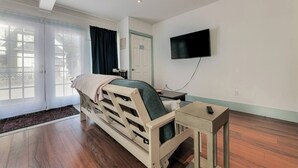 A modern room with a bed, a desk, a TV, and a large window. - Radiant Studio in the Heart of Bar Harbor (Bar Harbor)