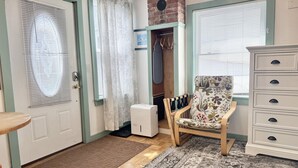 A room with a door, a coat rack, a chair, a dresser, and a patterned rug. - Cozy Studio in the Heart of Bar Harbor (Bar Harbor)