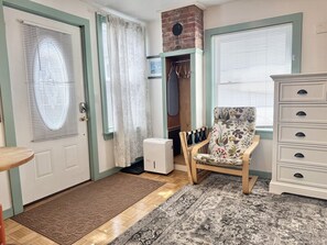 A room with a door, a coat rack, a chair, a dresser, and a patterned rug. - Cozy Studio in the Heart of Bar Harbor (Bar Harbor)