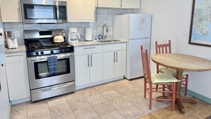 A kitchen with a stove, oven, microwave, refrigerator, and a dining table with chairs. - Cozy Studio in the Heart of Bar Harbor (Bar Harbor)