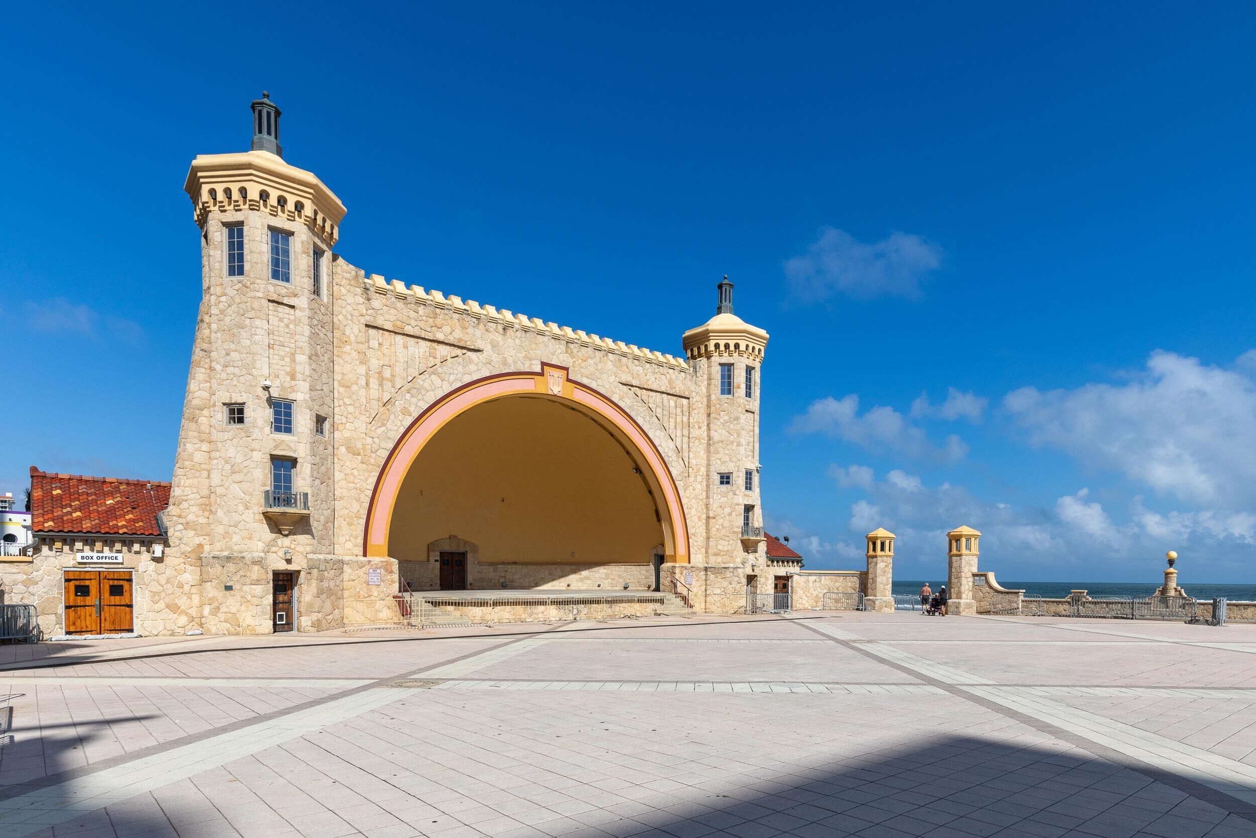 Un edificio storico in pietra con un grande ingresso ad arco, una piccola torre e un balcone.