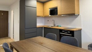 Cocina compacta con refrigerador, microondas, pileta y estufa. Cuenta con una mesa de madera y dos sillas.