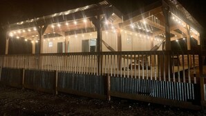 Una cabaña de madera con un porche cubierto y luces colgantes.