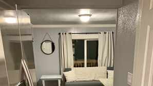 Una habitación pequeña con cama, una mesita y un banco.