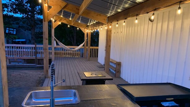 Un patio al aire libre con un lavamanos, una mesa y una hamaca.