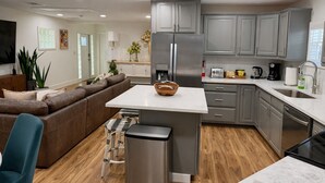 A modern kitchen with grey cabinets, a central island, and a built-in oven. - Downtown Clermont Boutique Garden Guest House (Clermont)