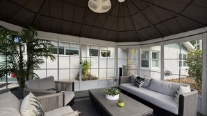 A sunroom with a high ceiling, large windows, and a central seating area with a sofa and chairs. - Downtown Clermont Boutique Garden Guest House (Clermont)