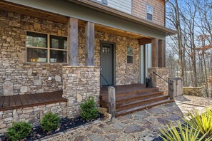 A stone house with a wooden porch and steps leading to the door. - Mountain View • Hot Tub • Sauna • Fire Pit (Blue Ridge)