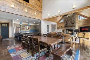 A spacious living area with a large wooden dining table, a fireplace, and a television displaying 'NETFLIX'. - Mountain View • Hot Tub • Sauna • Fire Pit (Blue Ridge)