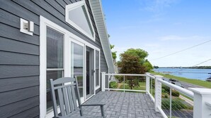 Een balkon met uitzicht op een wateroppervlak, een stoel en een leuning.