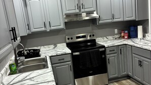 A modern kitchen with grey cabinets, stainless steel appliances, and a marble countertop. - Lake House Paradise
MTR (Slidell)