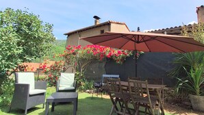 An outdoor patio with wicker chairs, a table, and a large umbrella.