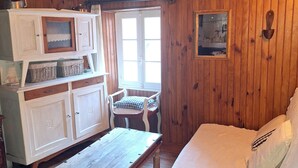 A cozy room with wooden walls, a bed, a wooden table, and a cabinet.