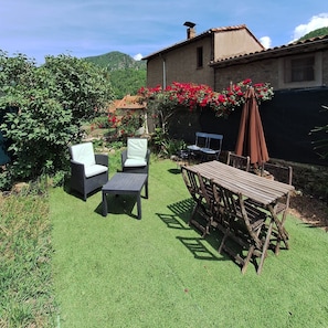An outdoor patio with wicker furniture, a wooden table, and a covered area.