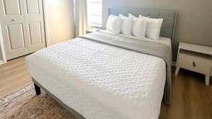 Een slaapkamer met een bed, nachtkastje en een deur.