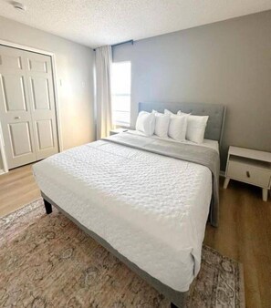 A bedroom with a bed, nightstand, and a door. - 7 Bd/ 4.5 Bath- Terra Verde Resort (Kissimmee)