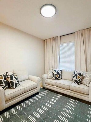 A living room with two sofas, patterned pillows, a patterned rug, a ceiling light, and a window with curtains. - 7 Bd/ 4.5 Bath- Terra Verde Resort (Kissimmee)
