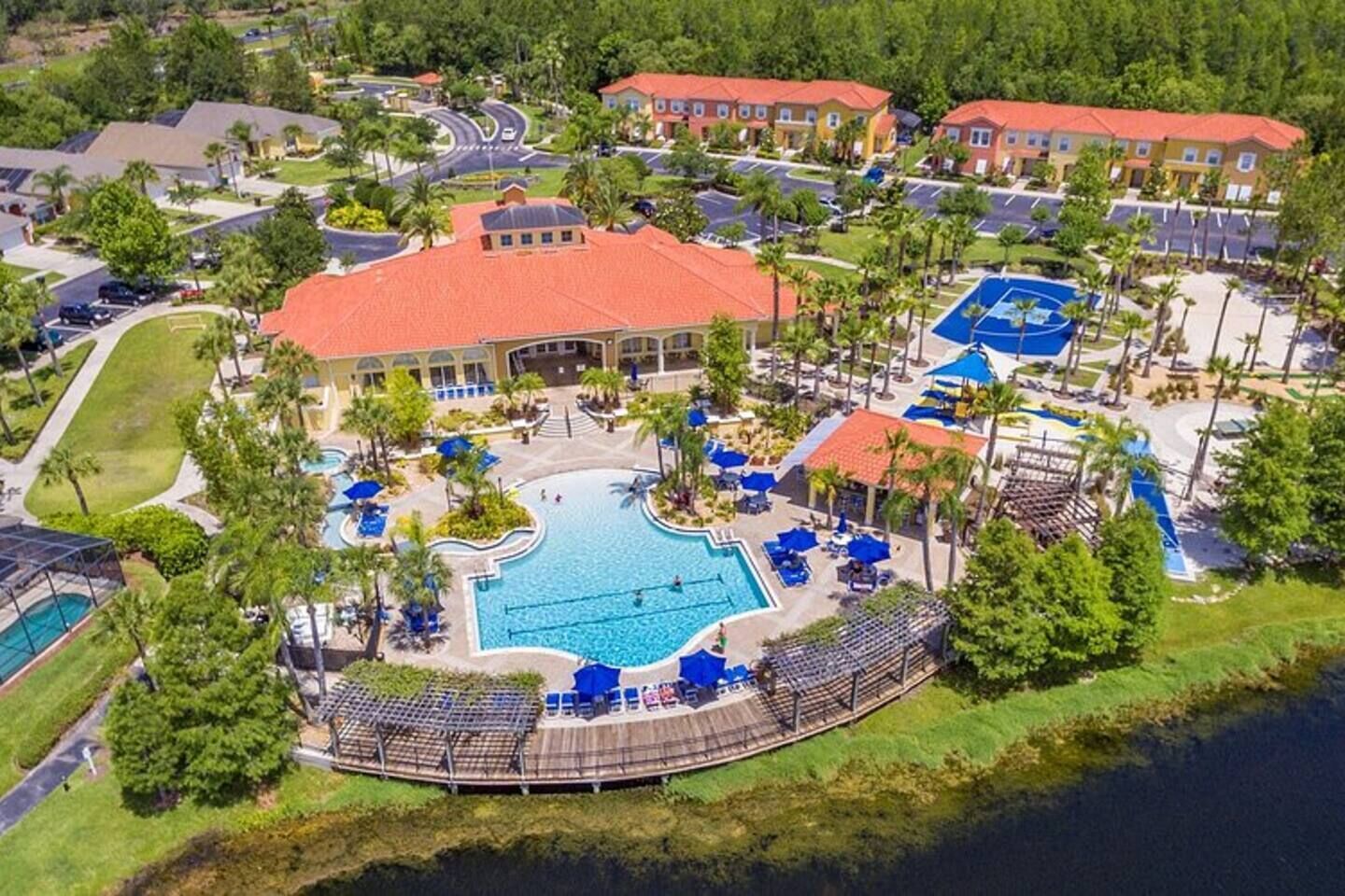 A resort with a central swimming pool, multiple buildings, and a landscaped area with palm trees.